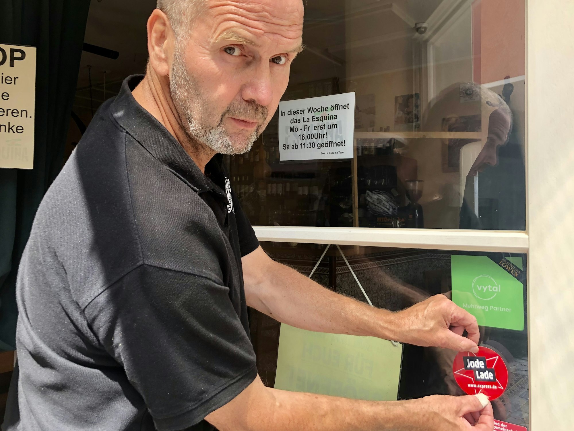 Dieter Niehoff klebt den „Jode Lade“-Sticker an die Eingangstür der Tapas-Bar.
