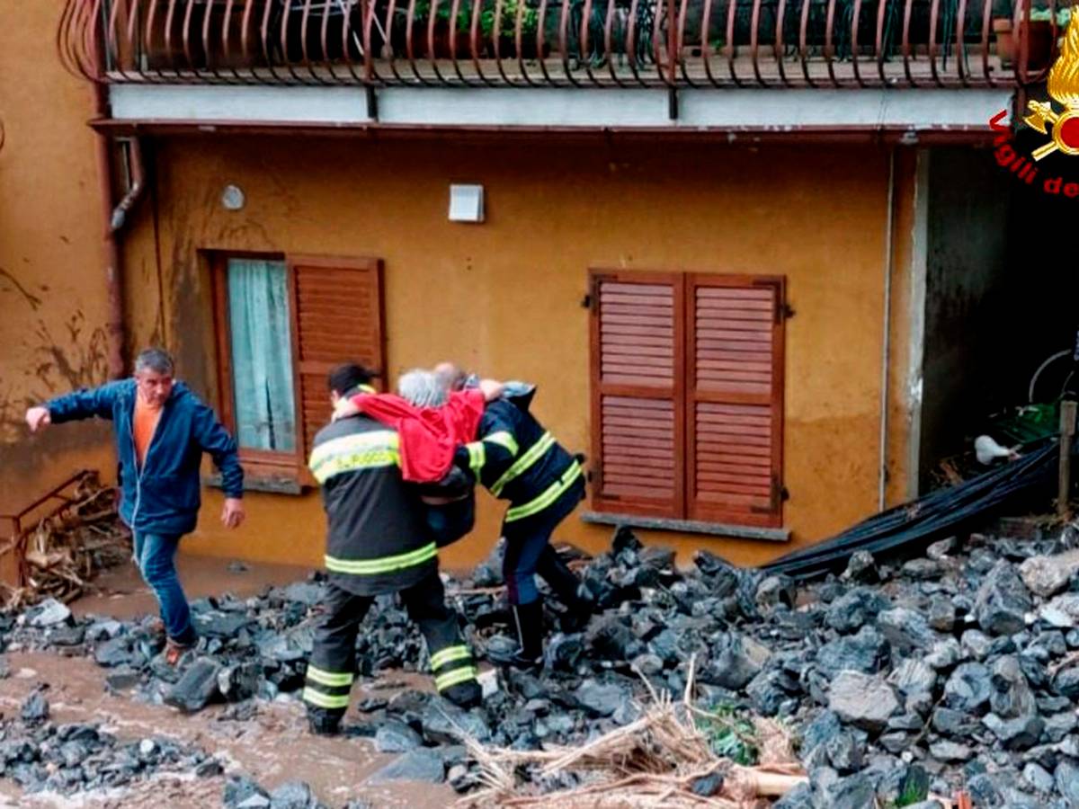 Einsatzkräfte der Feuerwehr retten eine ältere Frau aus ihrem Haus in Laglio am Comer See.