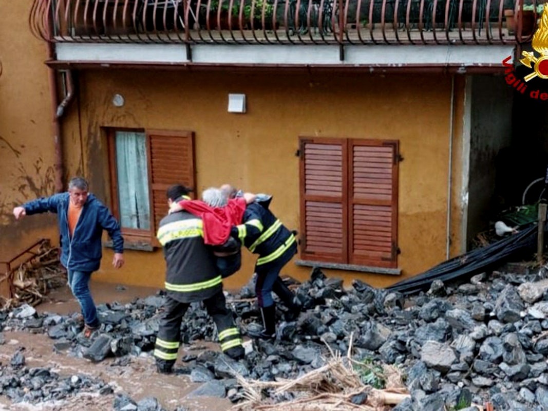 Einsatzkräfte der Feuerwehr retten eine ältere Frau aus ihrem Haus in Laglio am Comer See.