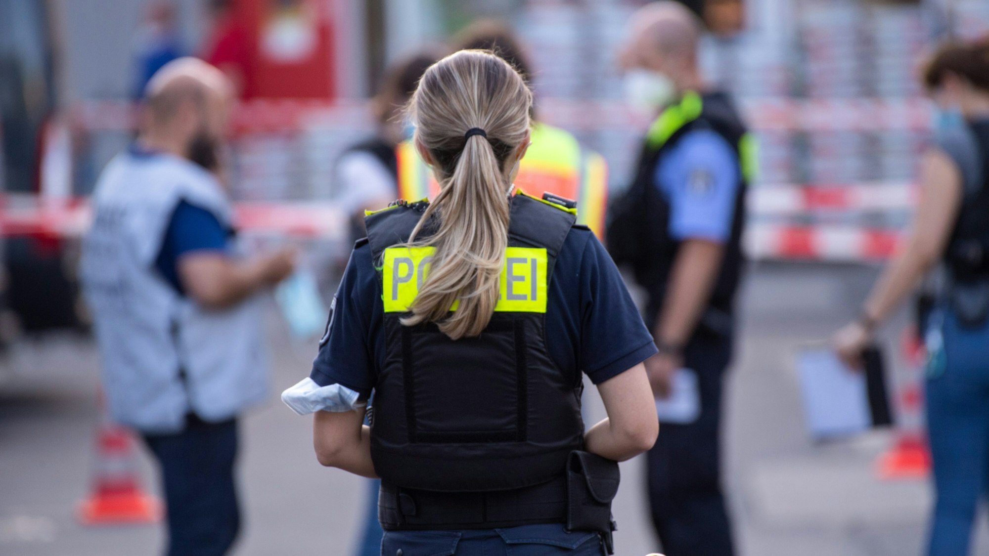 Polizisten stehen hinter Absperrbändern.