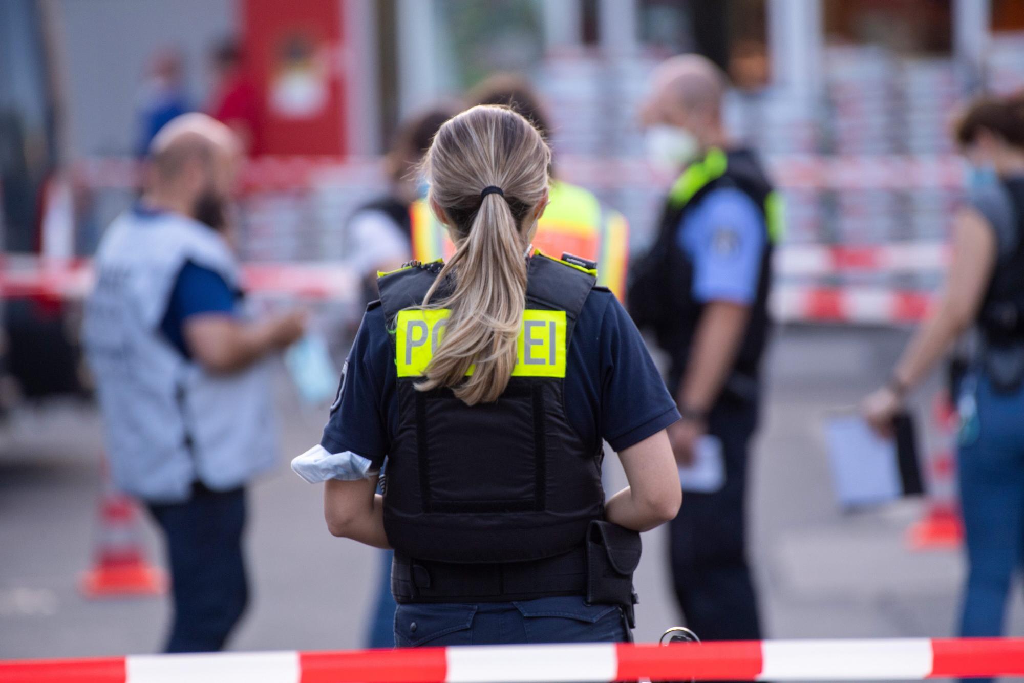 Eine Polzistin steht hinter einem roten Absperrband.