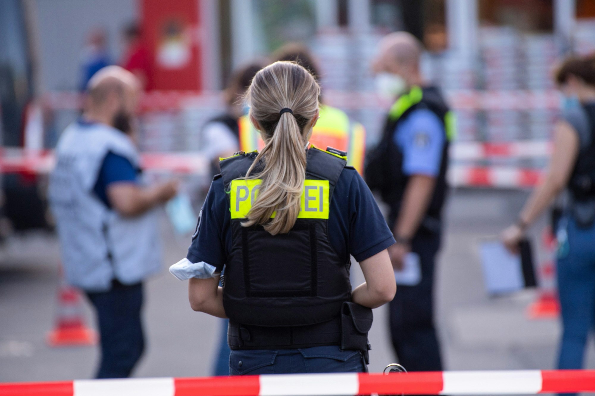 Eine Polzistin steht hinter einem roten Absperrband.