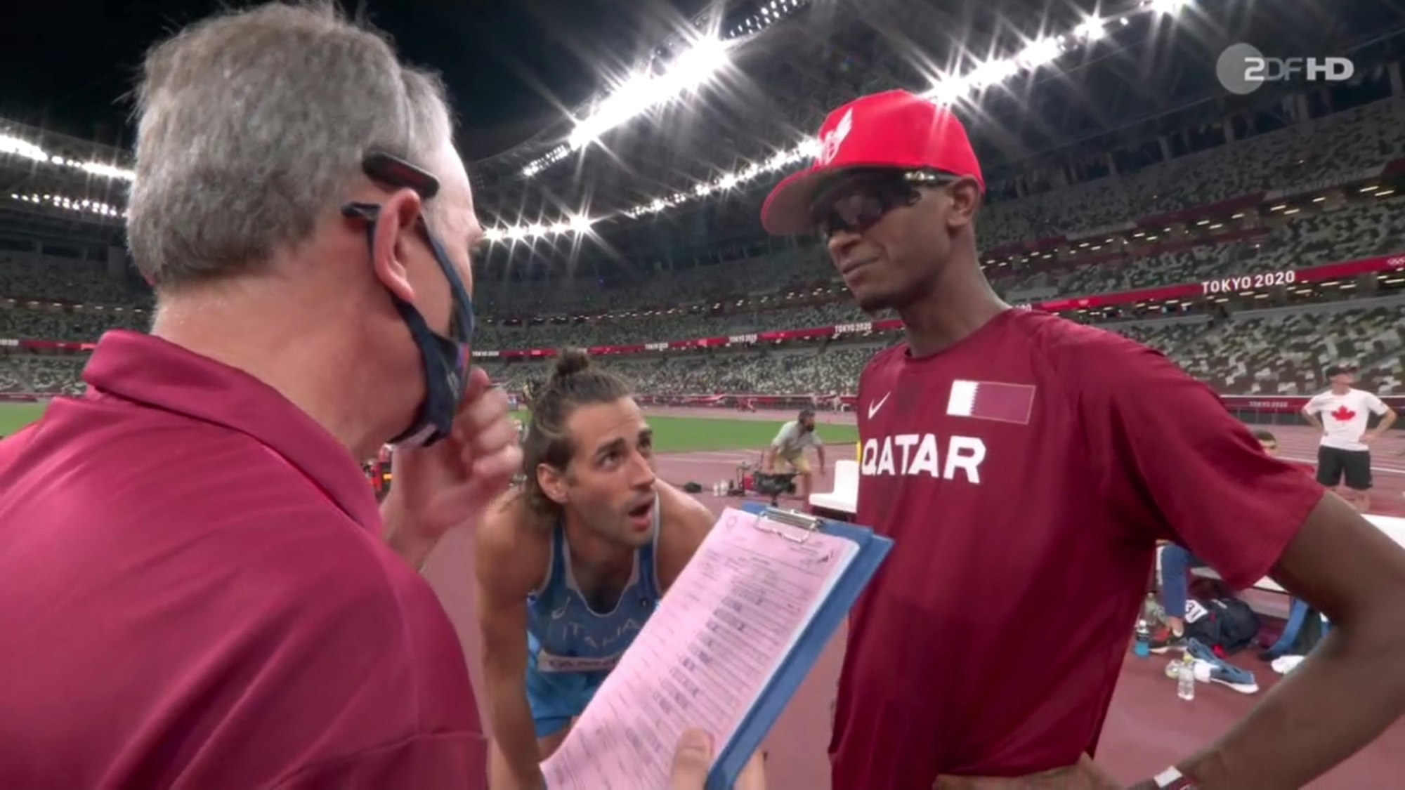 Gianmarco Tamberi und Mutaz Essa Barshim sprechen im Olympia-Finale mit einem Kampfrichter.