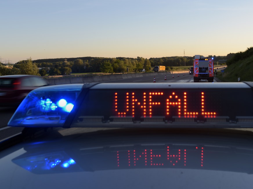 Auf einem Polizeifahrzeug warnt auf der Autobahn A8 eine Leuchtschrift vor einer Unfallstelle.