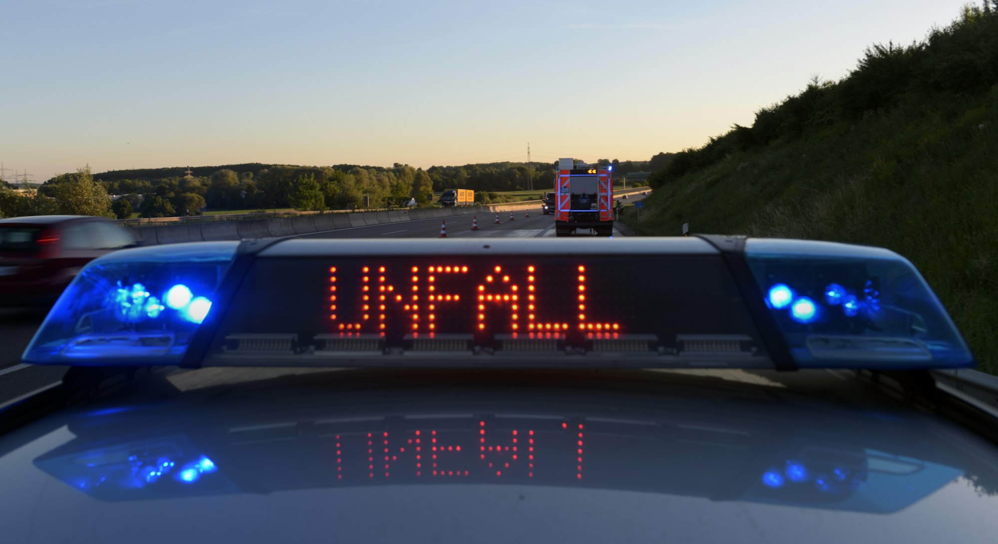 Auf einem Polizeifahrzeug warnt auf der Autobahn A8 eine Leuchtschrift vor einer Unfallstelle.