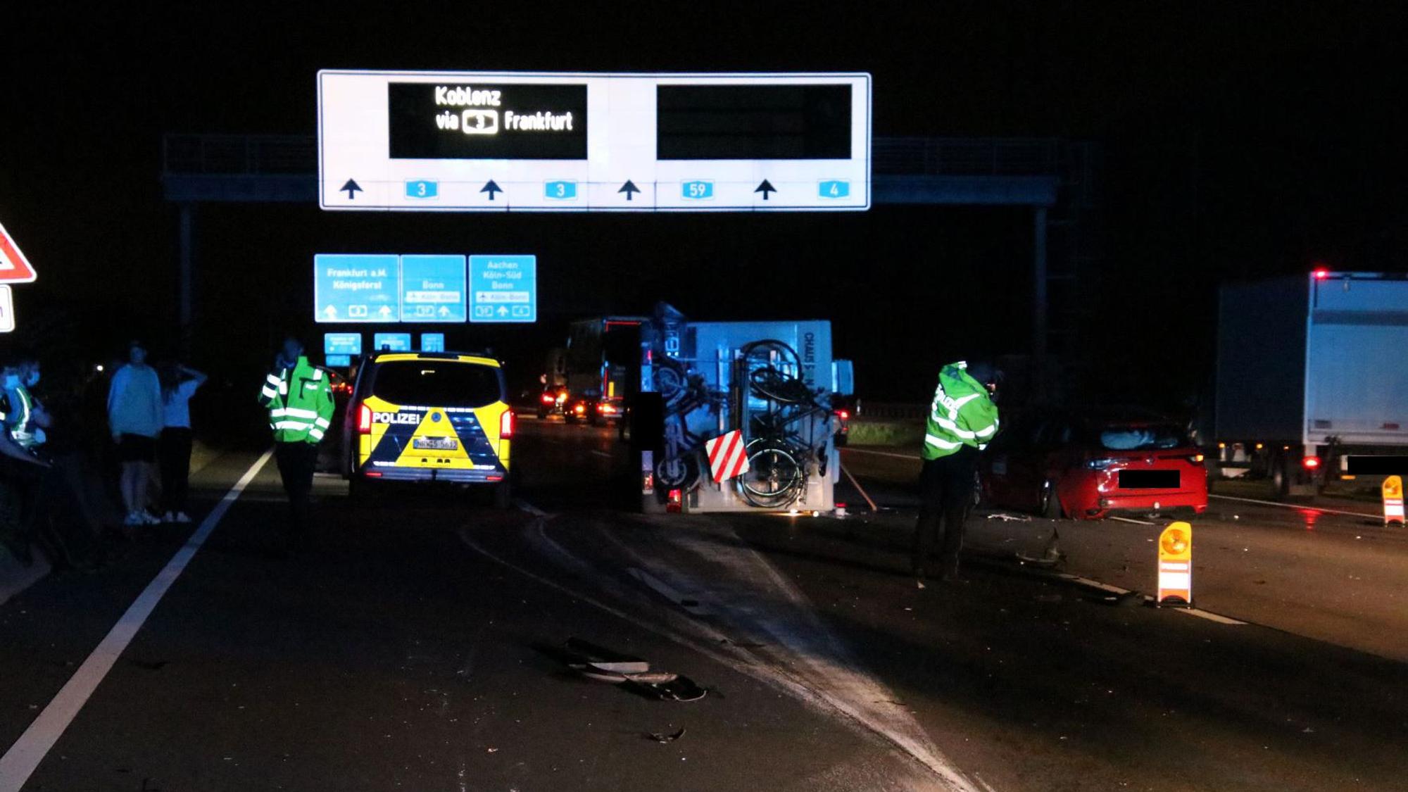 Einsatzkräfte sowie ein Polizeifahrzeug stehen nachts auf der Autobahn.