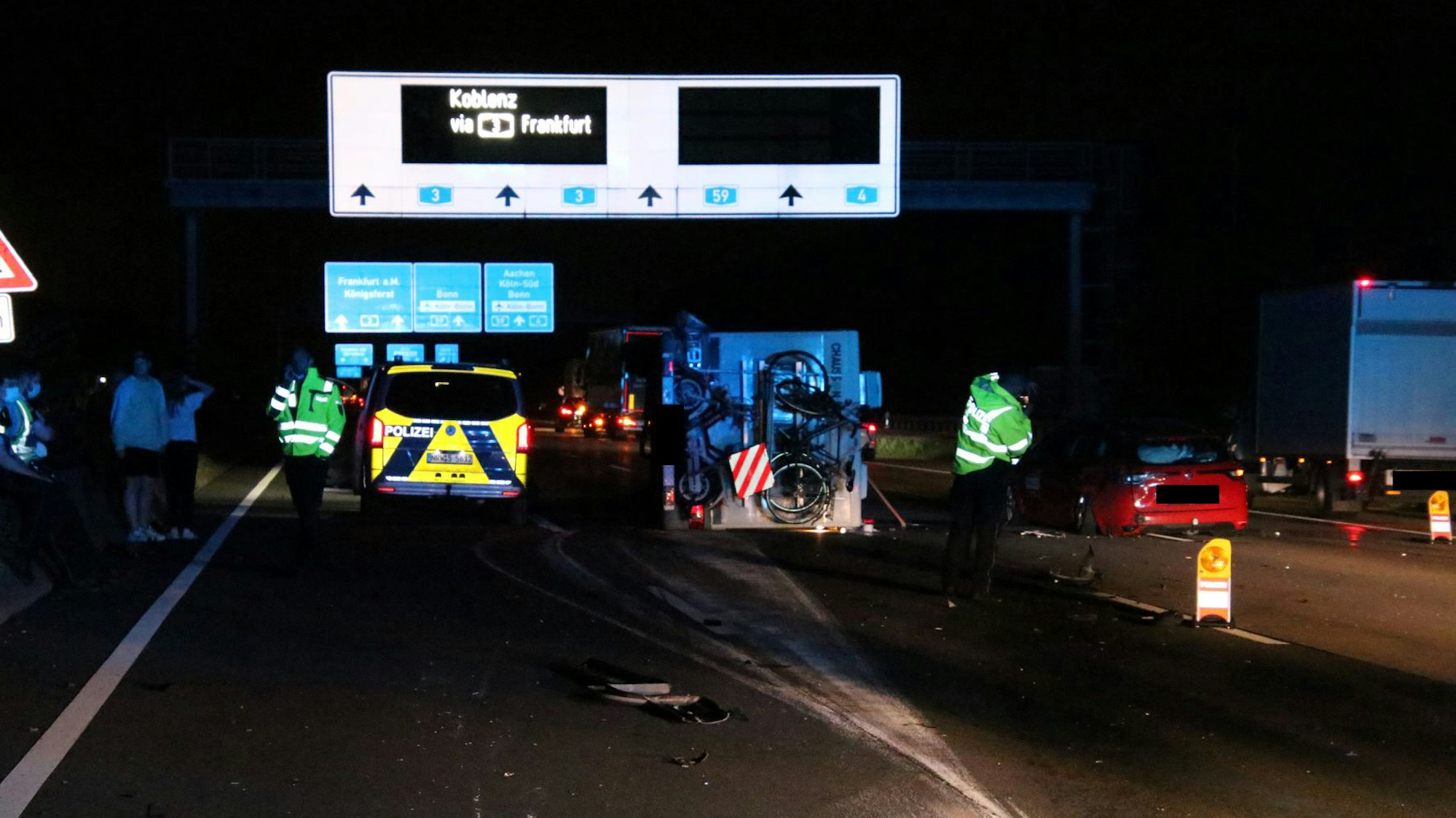 Einsatzkräfte sowie ein Polizeifahrzeug stehen nachts auf der Autobahn.