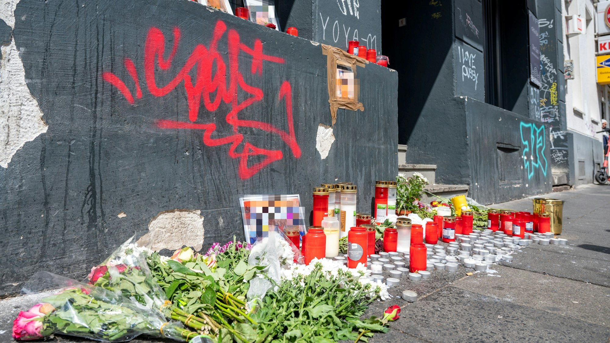Blumen und Kerzen sind am Tatort auf der Zülpicher Straße niedergelegt.