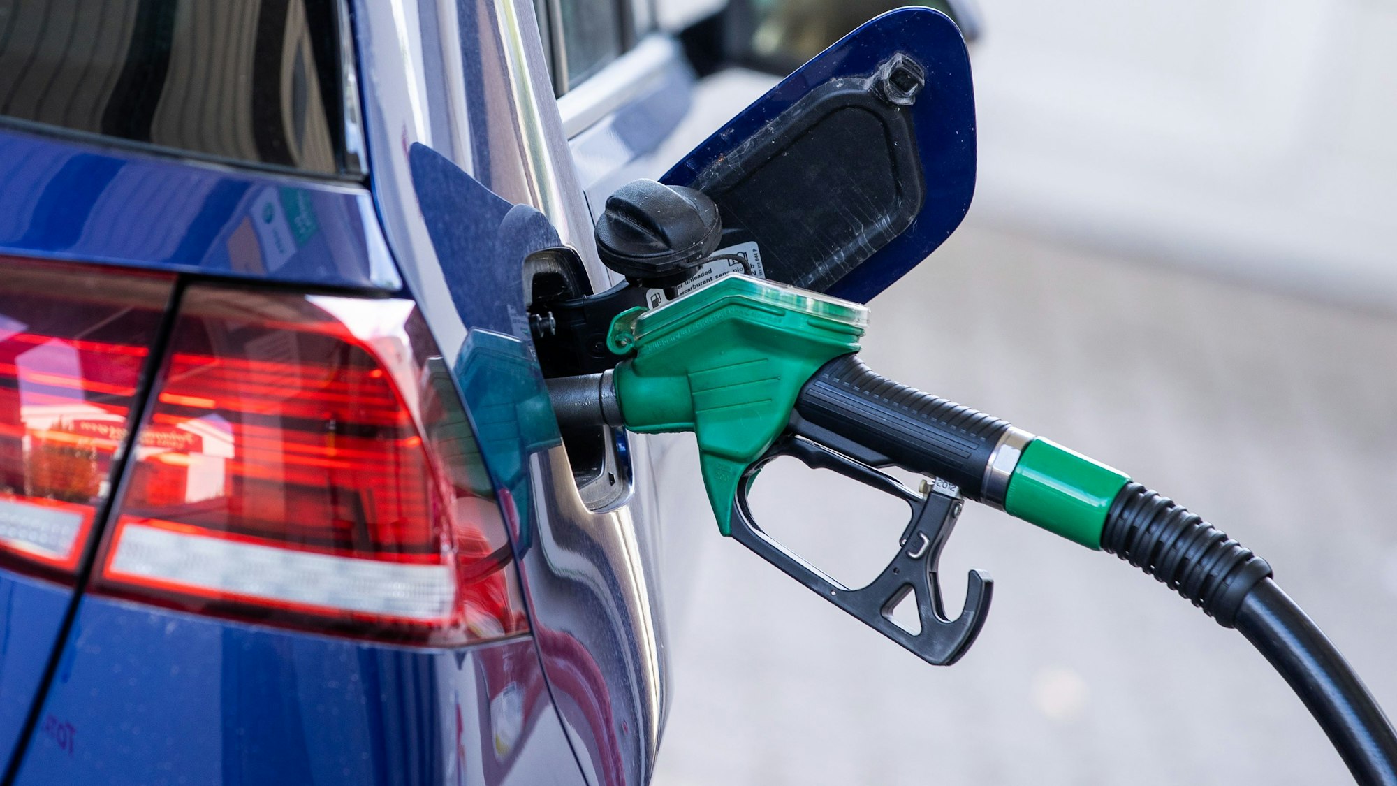 Spritpreise steigen: Eine Zapfpistole für Super-Kraftstoff steckt in einer Tankstelle im Tankstutzen eines Autos.