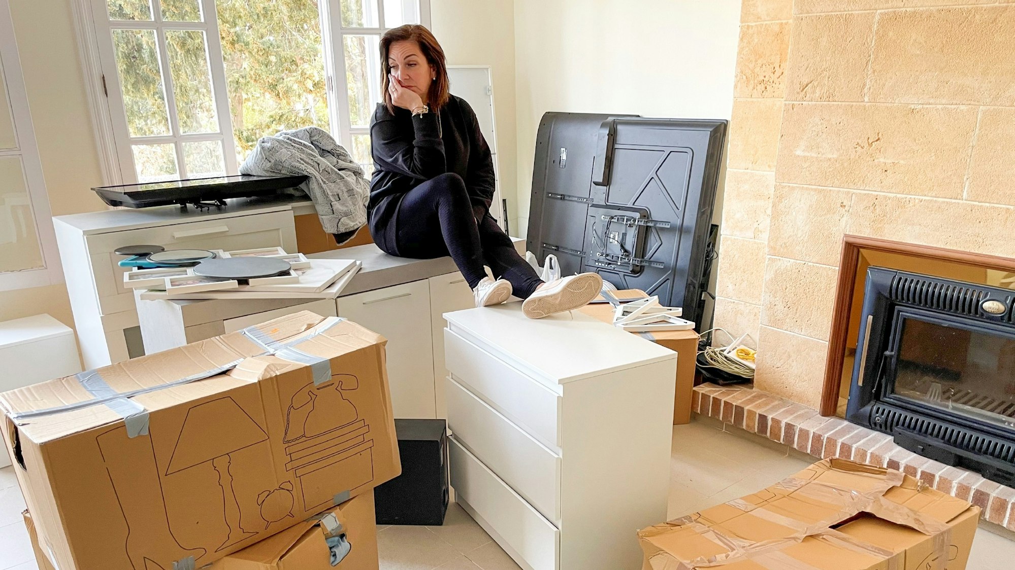 Danni Büchner sitzt auf ihren Umzugskartons, den Kopf hat sie auf die Hand gestützt.