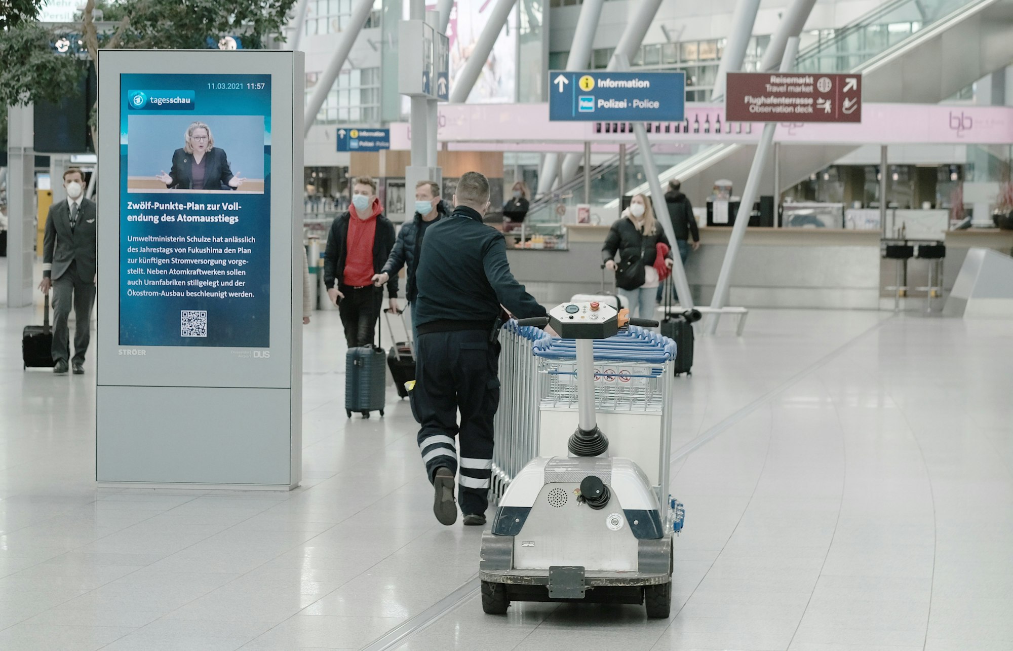 Menschen gehen durch den fast leeren Flughafen Düsseldorf.