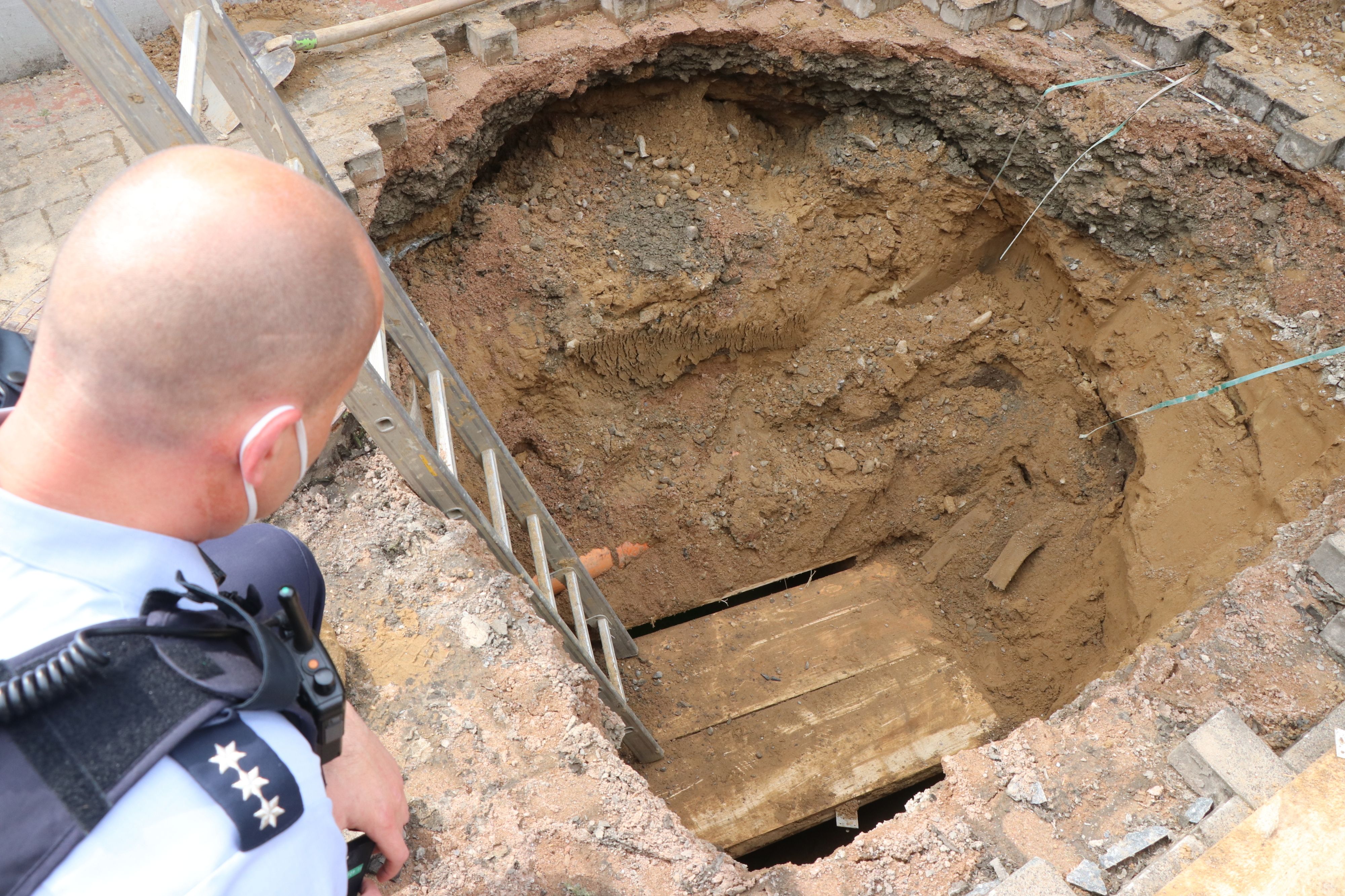 Ein Polizist schaut auf das Loch eines Tunnels, den Unbekannte zur Volksbank gegraben haben.