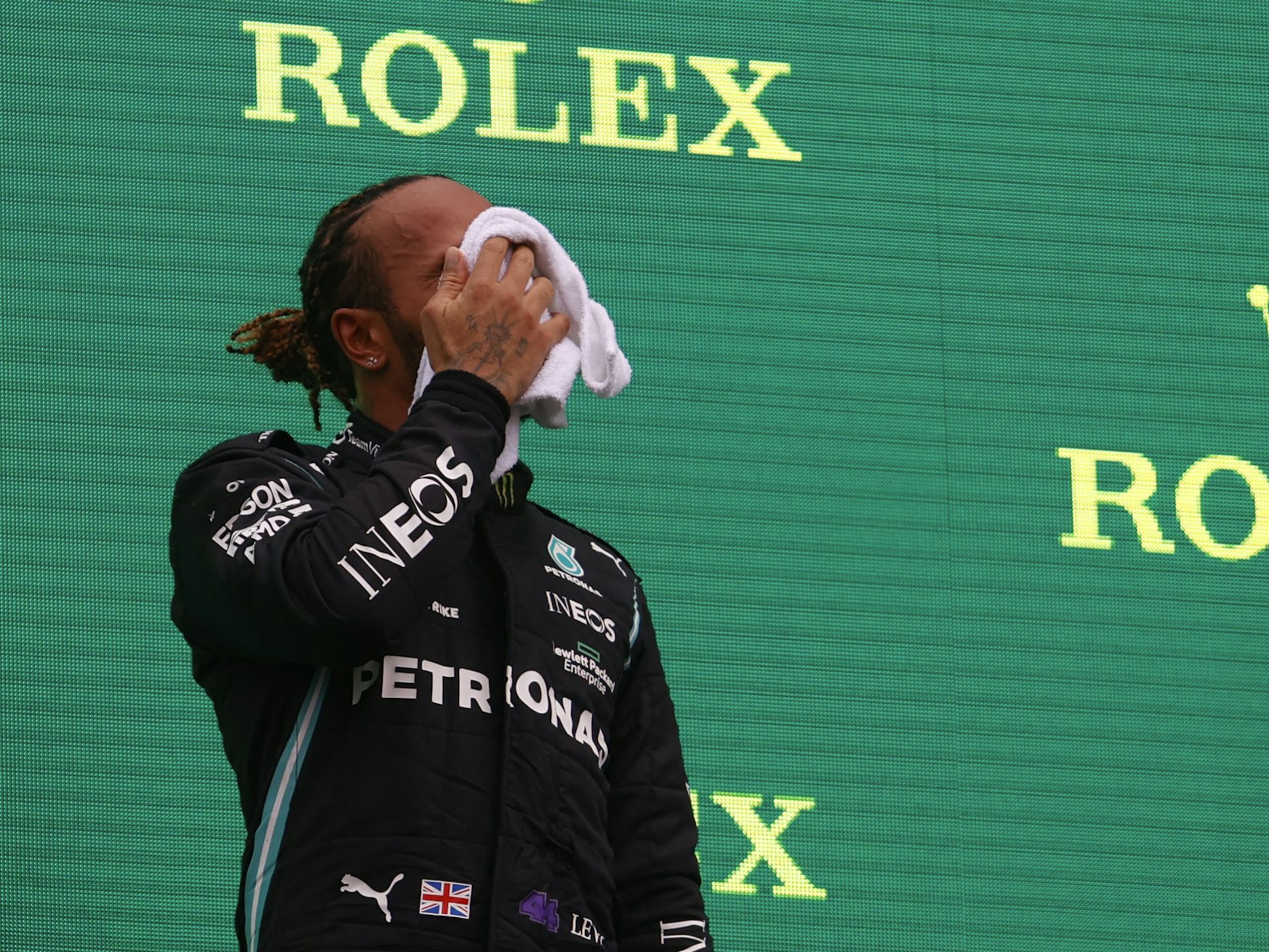 Formel 1: Lewis Hamilton wischt sich das Gesicht trocken auf dem Podium.