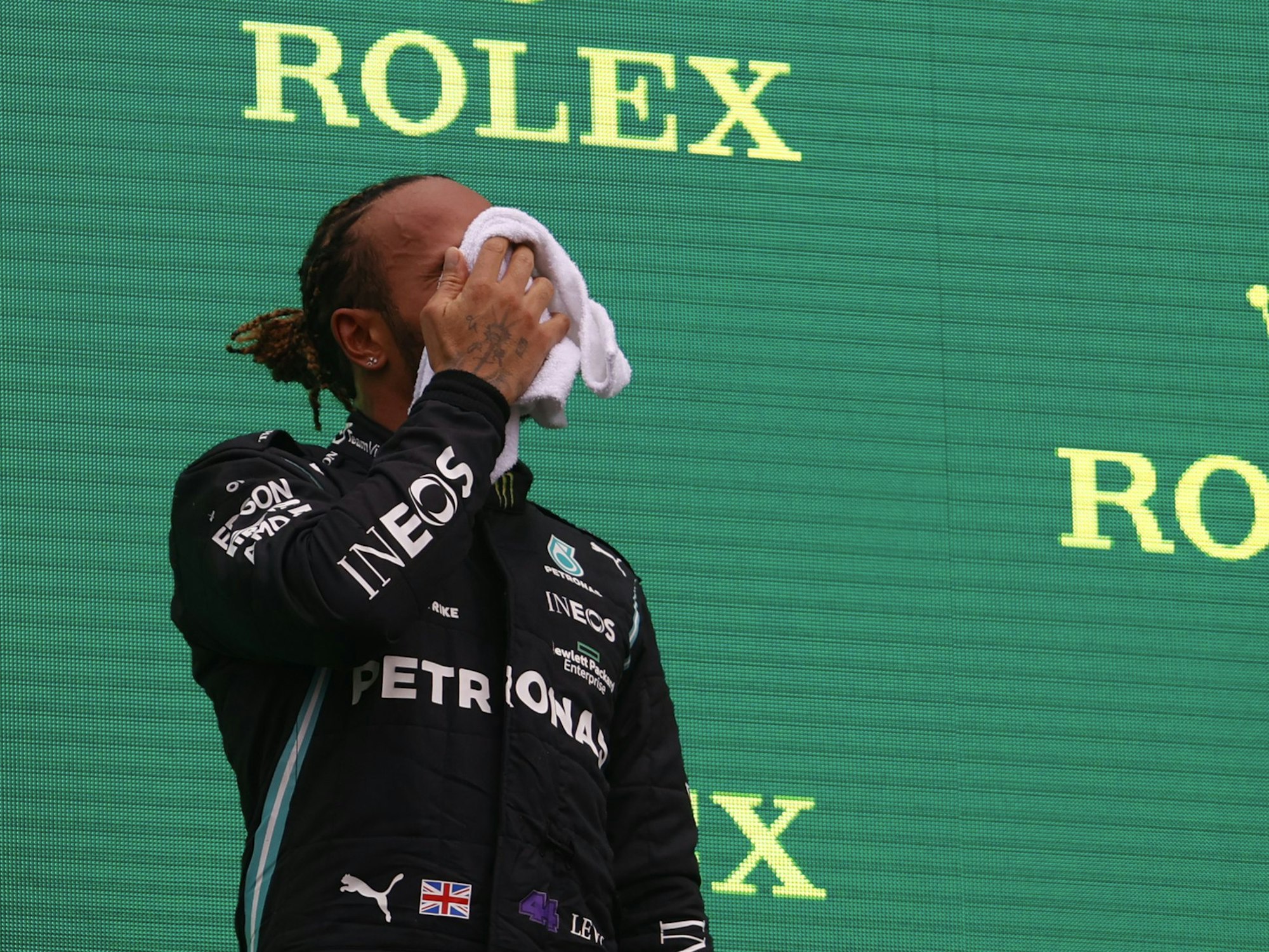 Formel 1: Lewis Hamilton wischt sich das Gesicht trocken auf dem Podium.