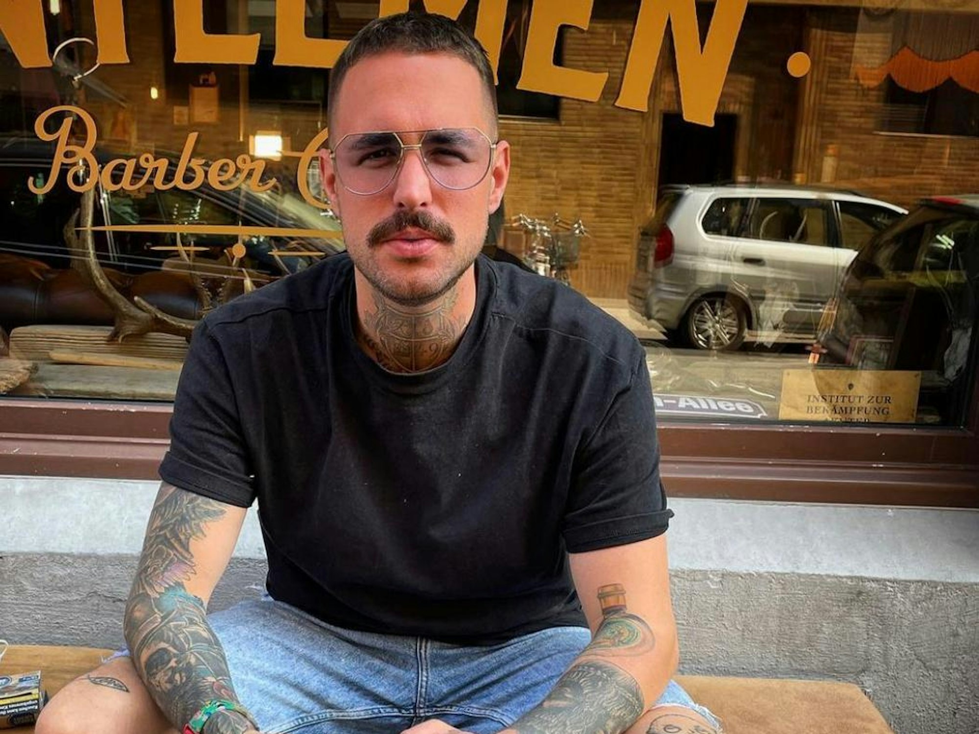 Der Kölner Elmar Heilf sitzt vor dem Gentleman Barber Club.