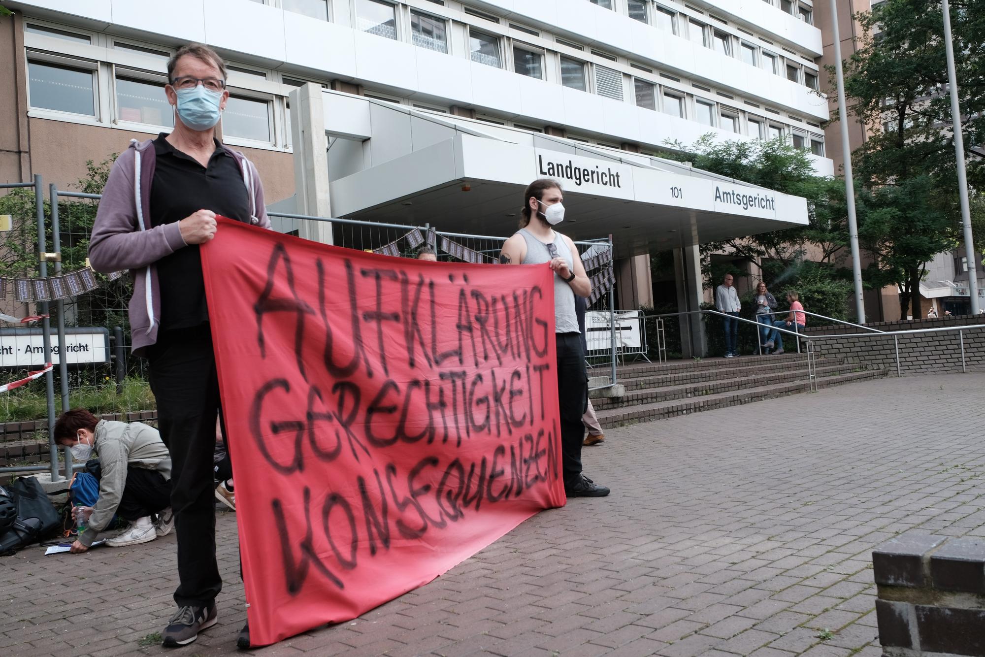 Demonstranten halten ein Plakat vor dem Kölner Landgericht hoch.