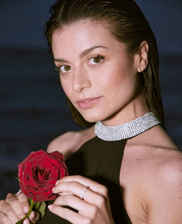 „Bachelorette“ Maxim Herbord am Strand. Sie hält eine Rose in der Hand.