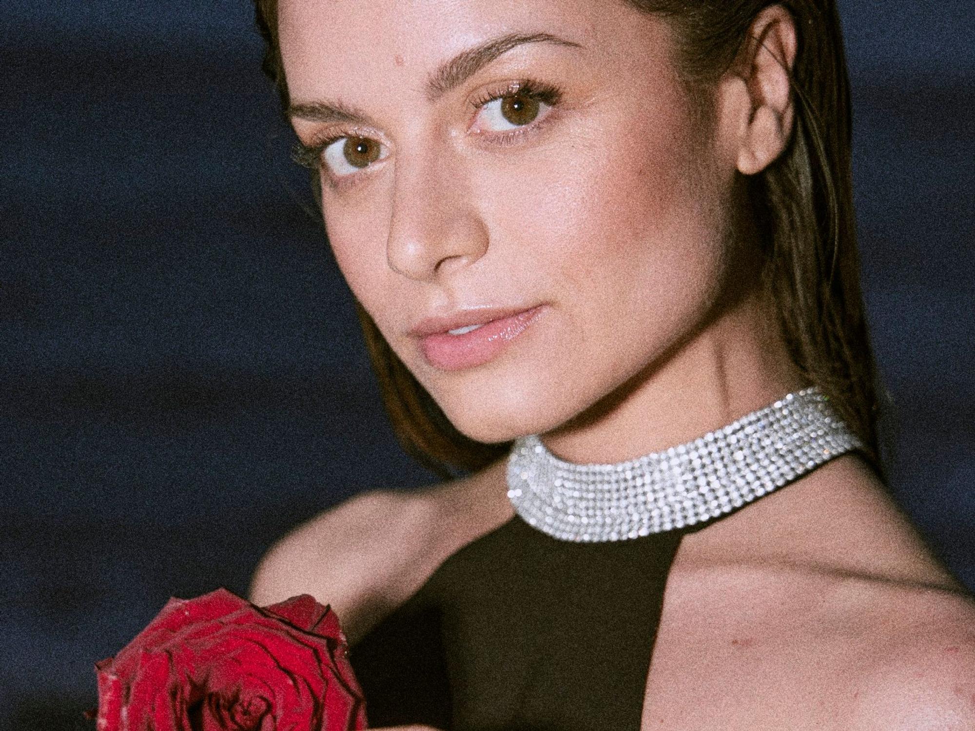 „Bachelorette“ Maxim Herbord am Strand. Sie hält eine Rose in der Hand.