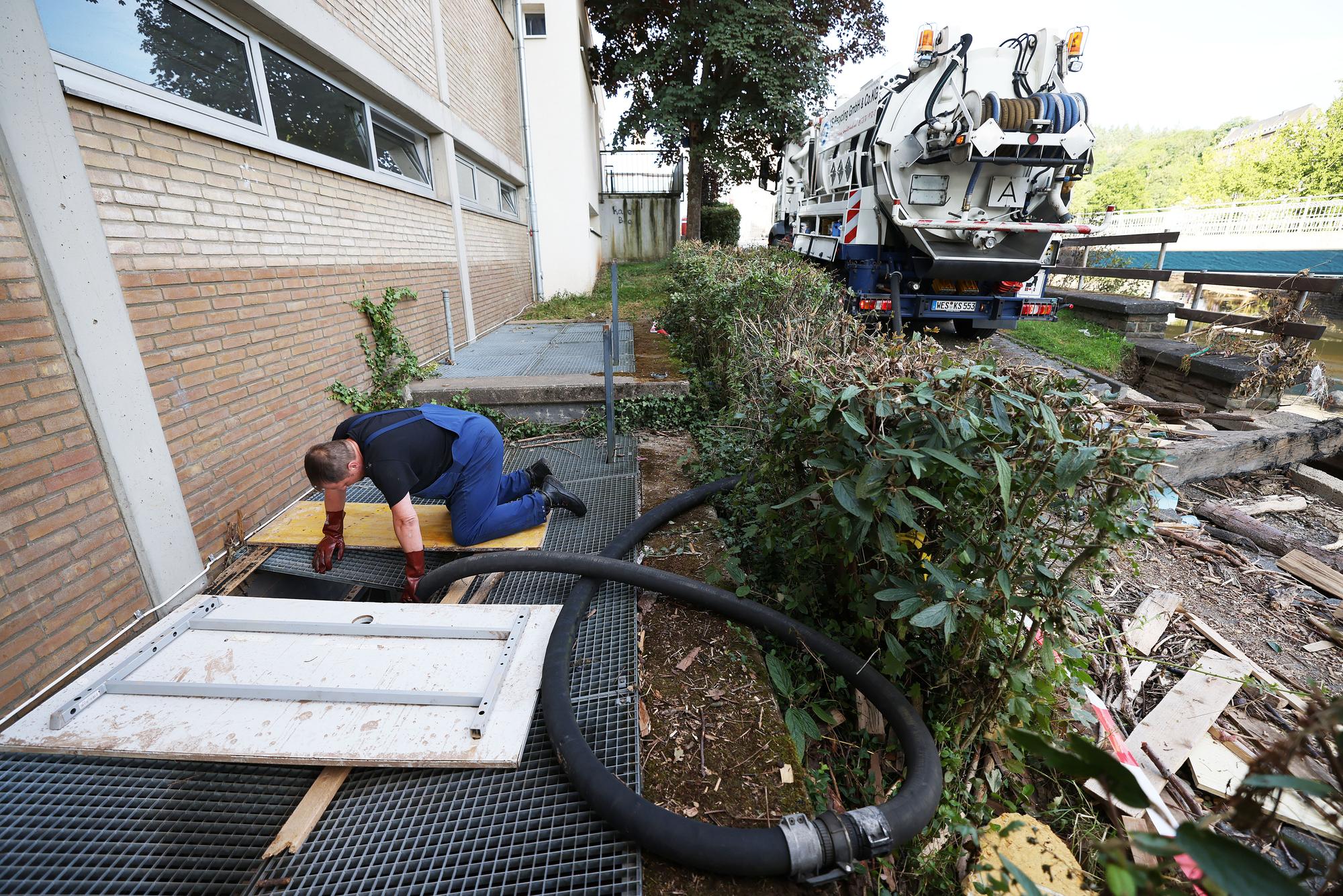 NRW: Ein Mitarbeiter des Spezialentsorgers saugt kontaminiertes Wasser mit einem Schlauch aus einer Schule.