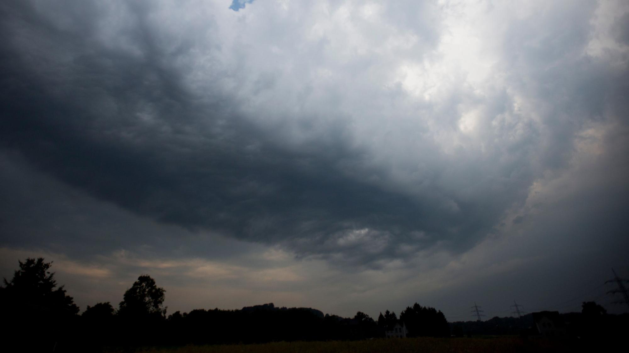 Dunkle Gewitterwolken ziehen über ein Feld in Hattingen (Nordrhein-Westfalen).