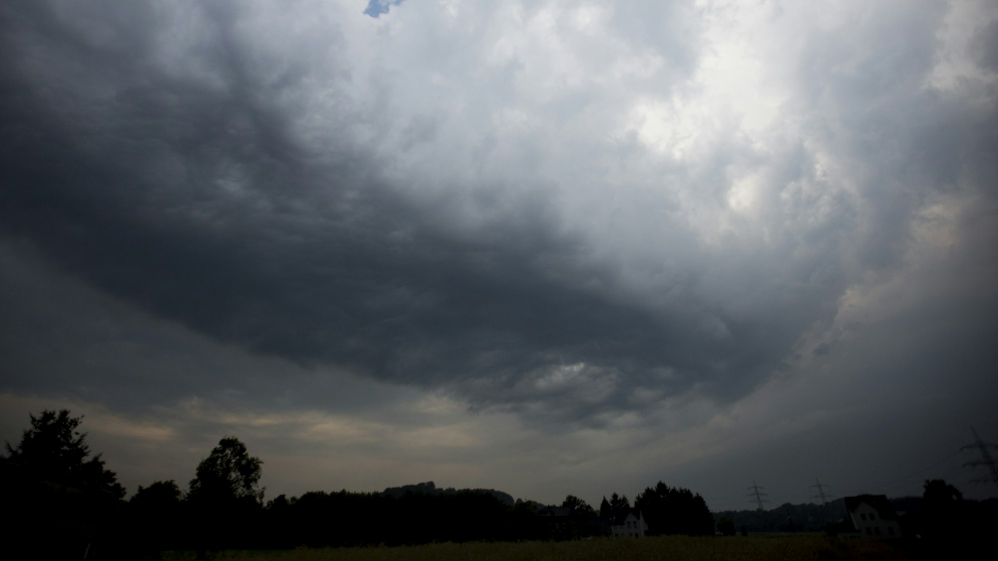 Dunkle Gewitterwolken ziehen über ein Feld in Hattingen (Nordrhein-Westfalen).