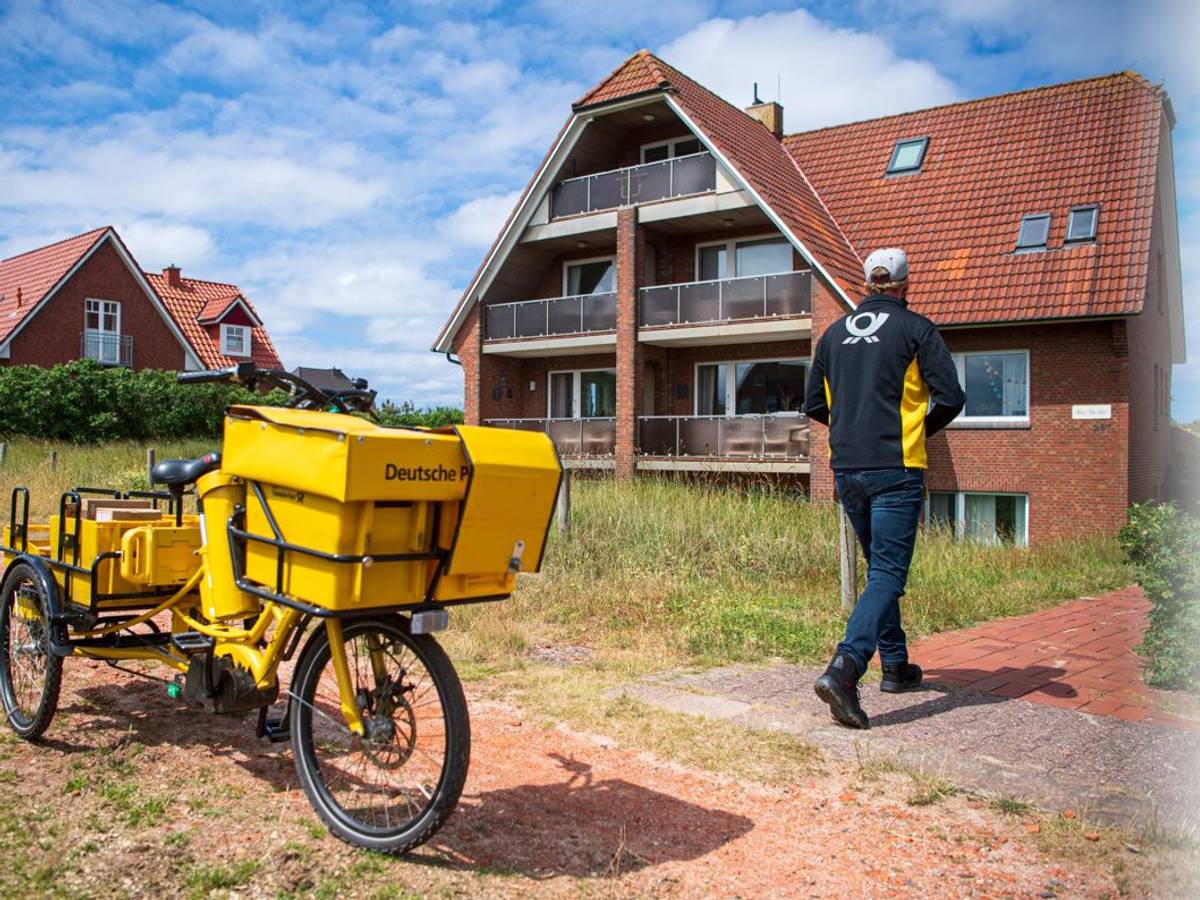 Ein Postbote bringt Post zu einem Haus auf Baltrum.