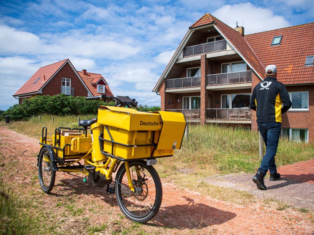 Ein Postbote bringt Post zu einem Haus auf Baltrum.