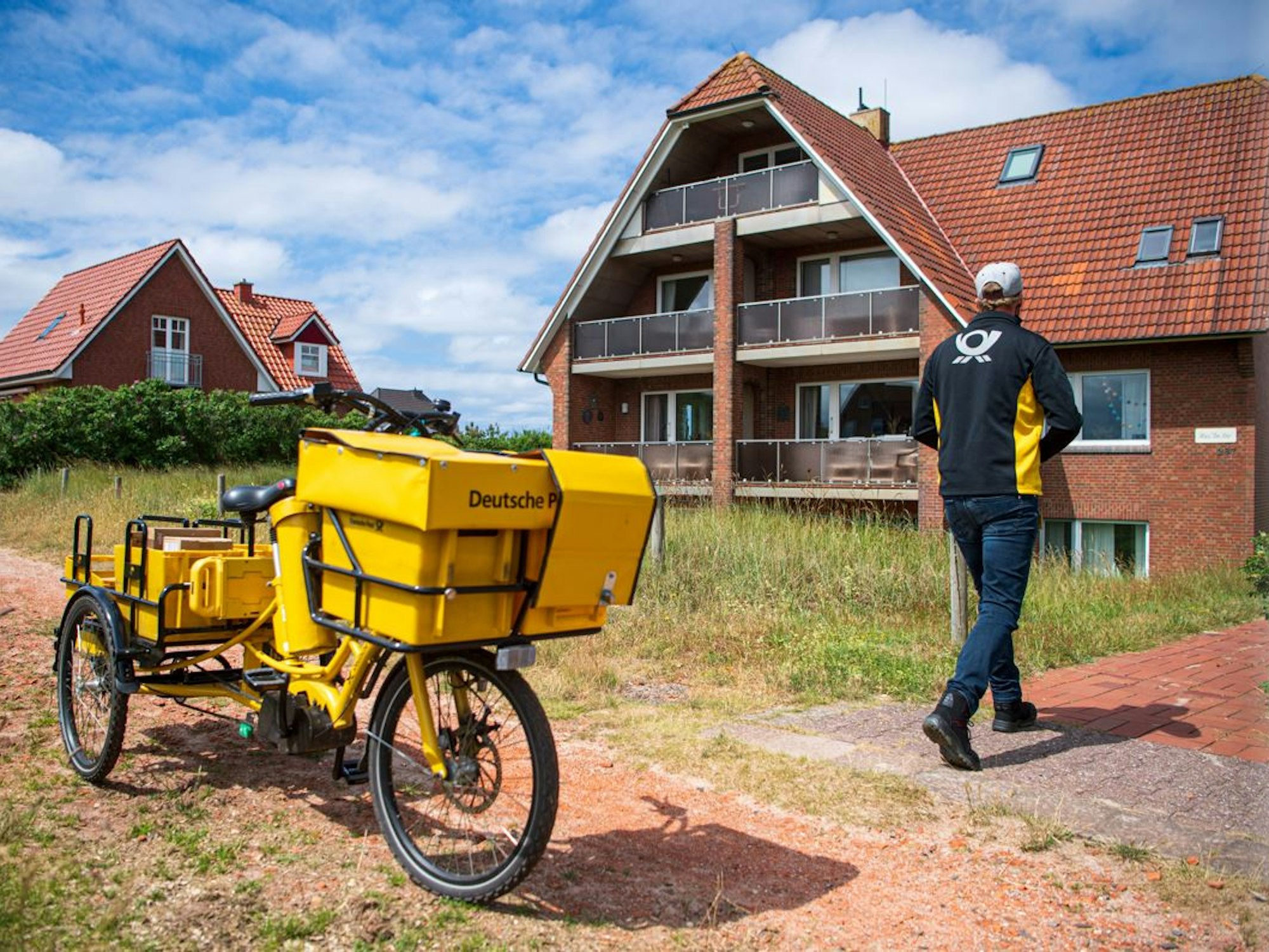 Ein Postbote bringt Post zu einem Haus auf Baltrum.