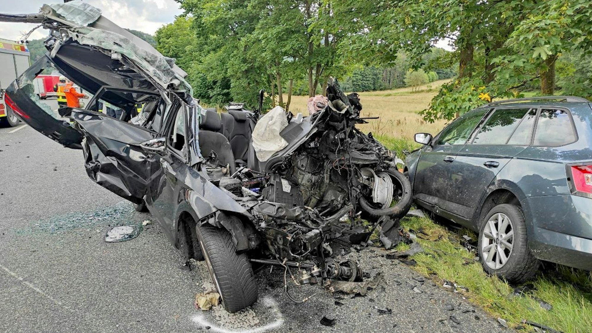 04.08.2021, Hessen, Eschenburg-Simmersbach: Das Wrack eines Autos liegt auf der Bundesstraße 253 (Dillenburg-Biedenkopf) zwischen Eschenburg-Simmersbach und Breidenbach-Oberdieten.