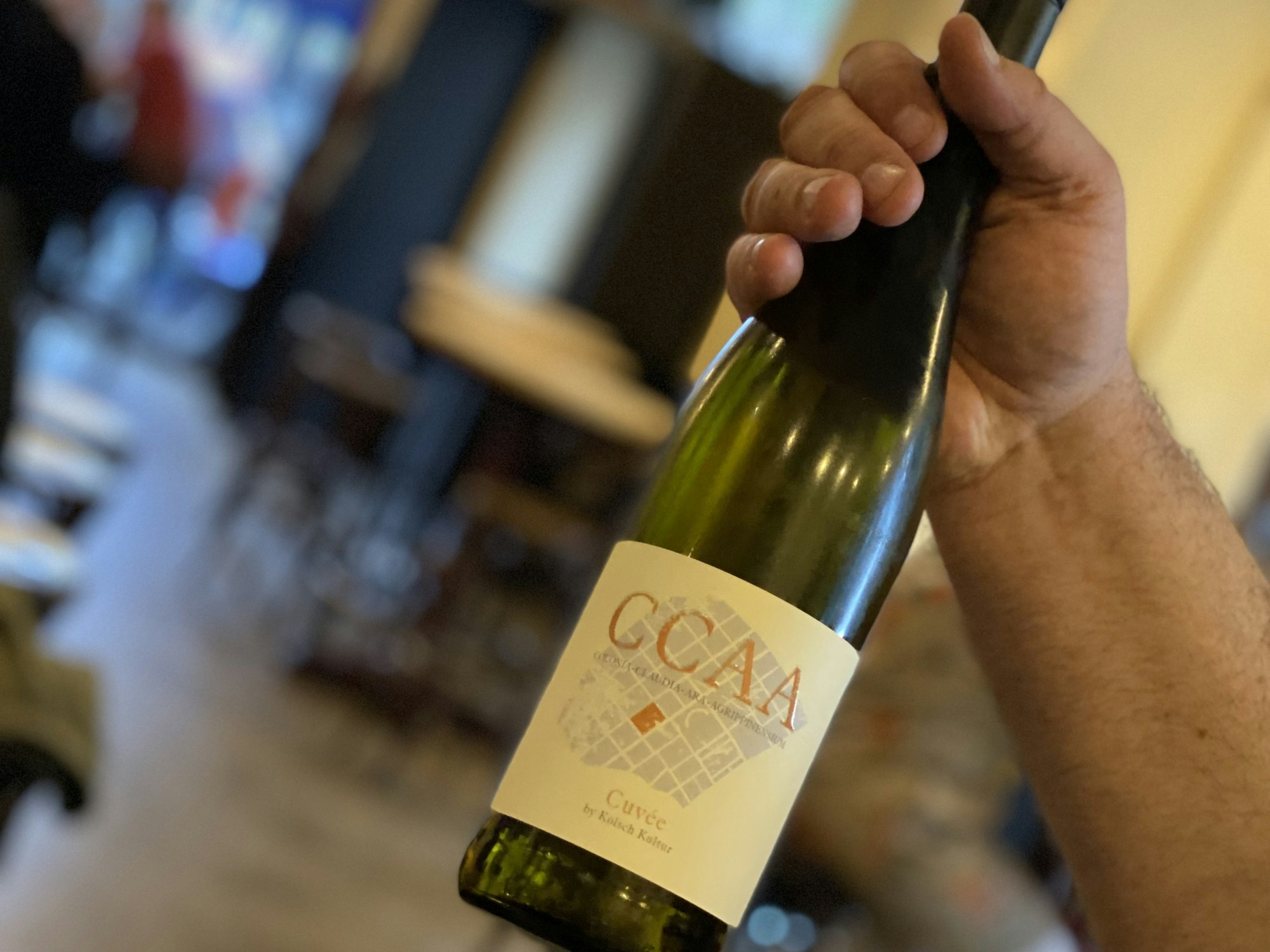 Jemand hält im Lokal eine Flasche Wein in der Hand.