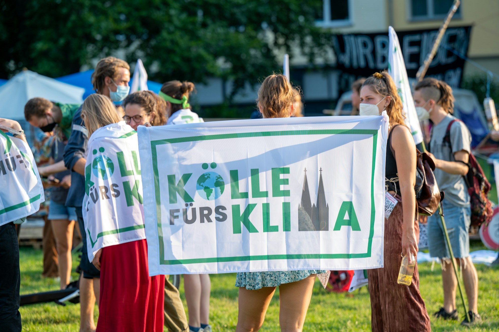 Eine Aktivistin hält bei einer Demonstration die „Kölle fürs Klima“-Flagge nach oben.