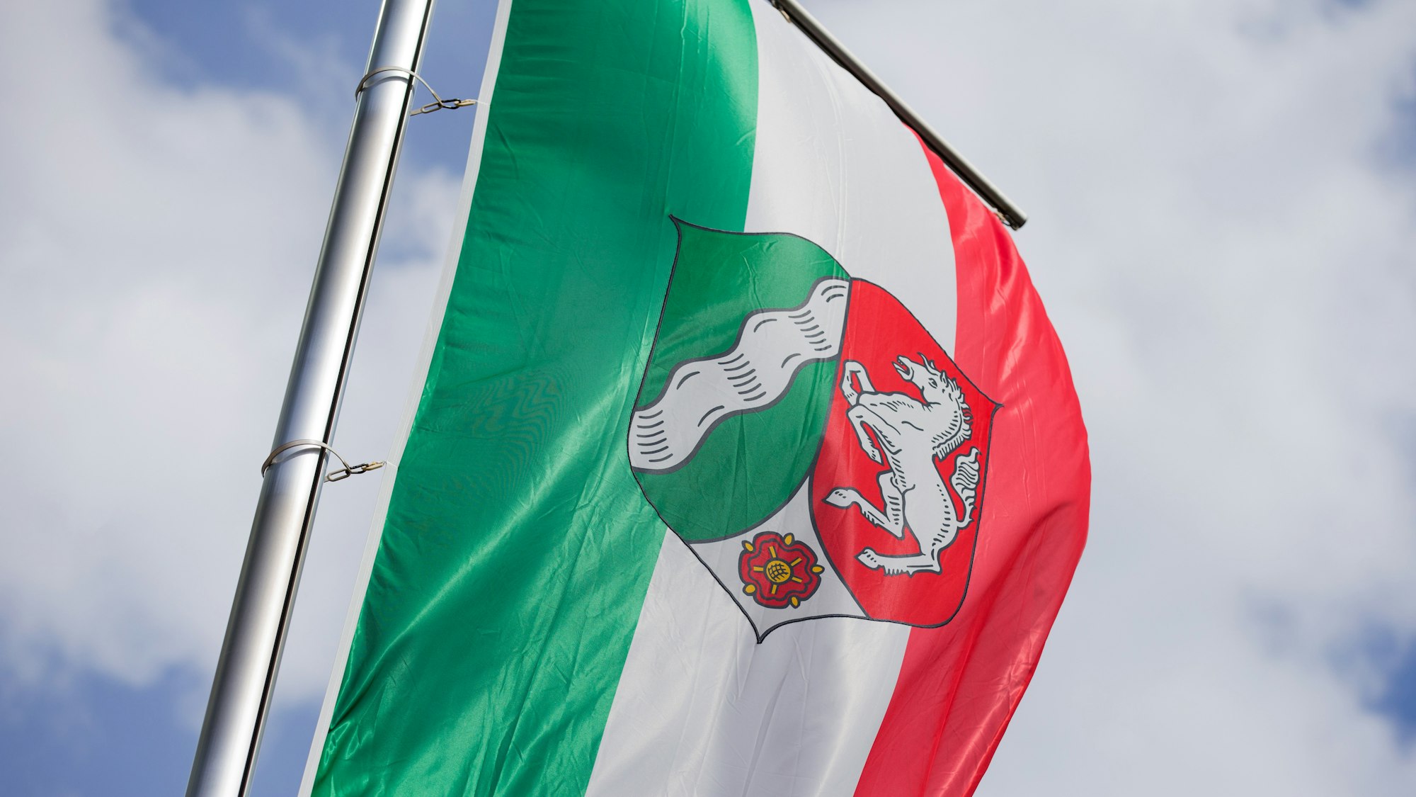 ARCHIV - Eine Flagge mit dem Landeswappen von Nordrhein-Westfalen weht am 29.06.2016 vor der Staatskanzlei in Düsseldorf (Nordrhein-Westfalen).