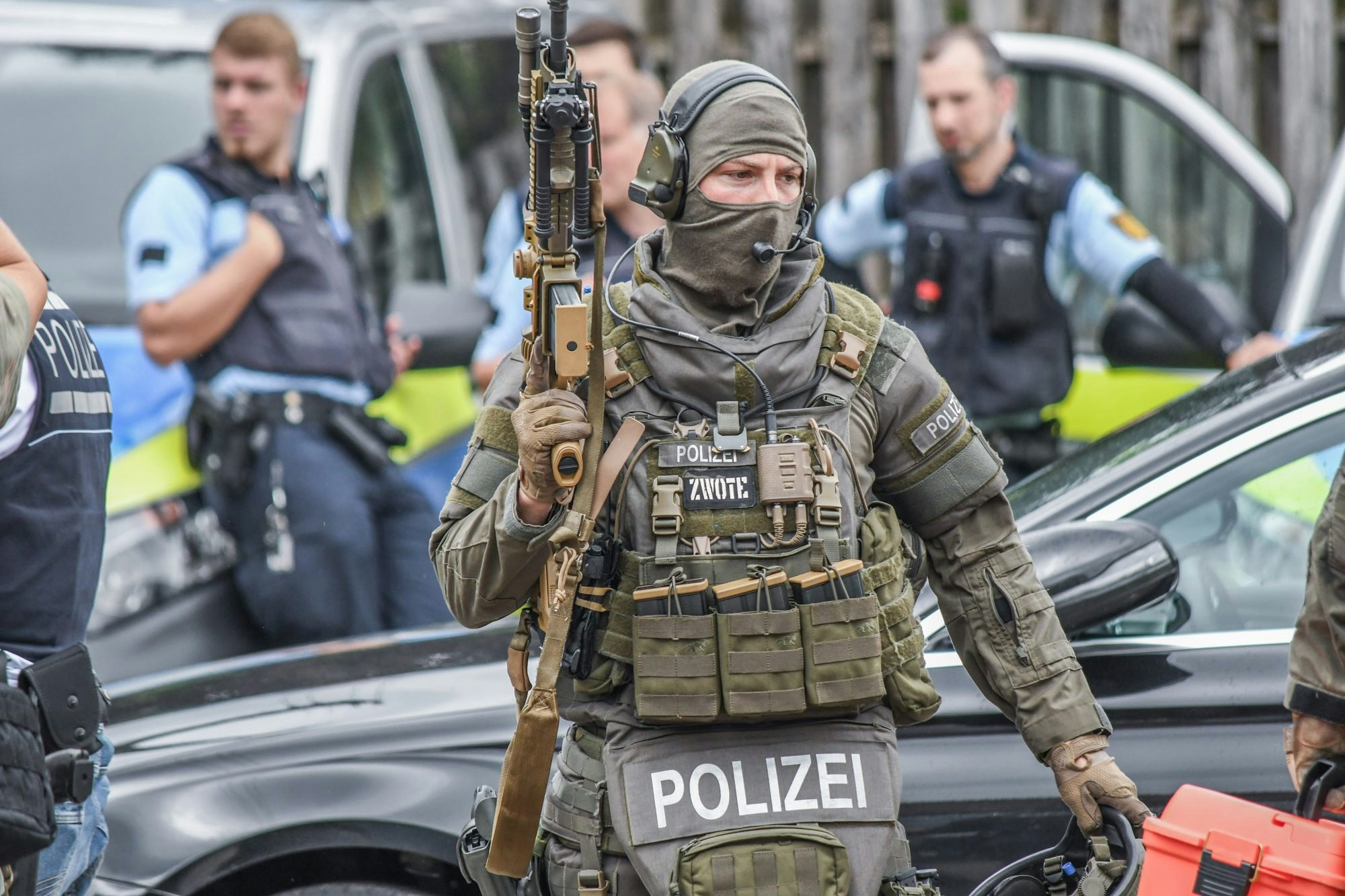Ein Polizist steht vermummt und mit Waffe zwischen seinen Kollegen.