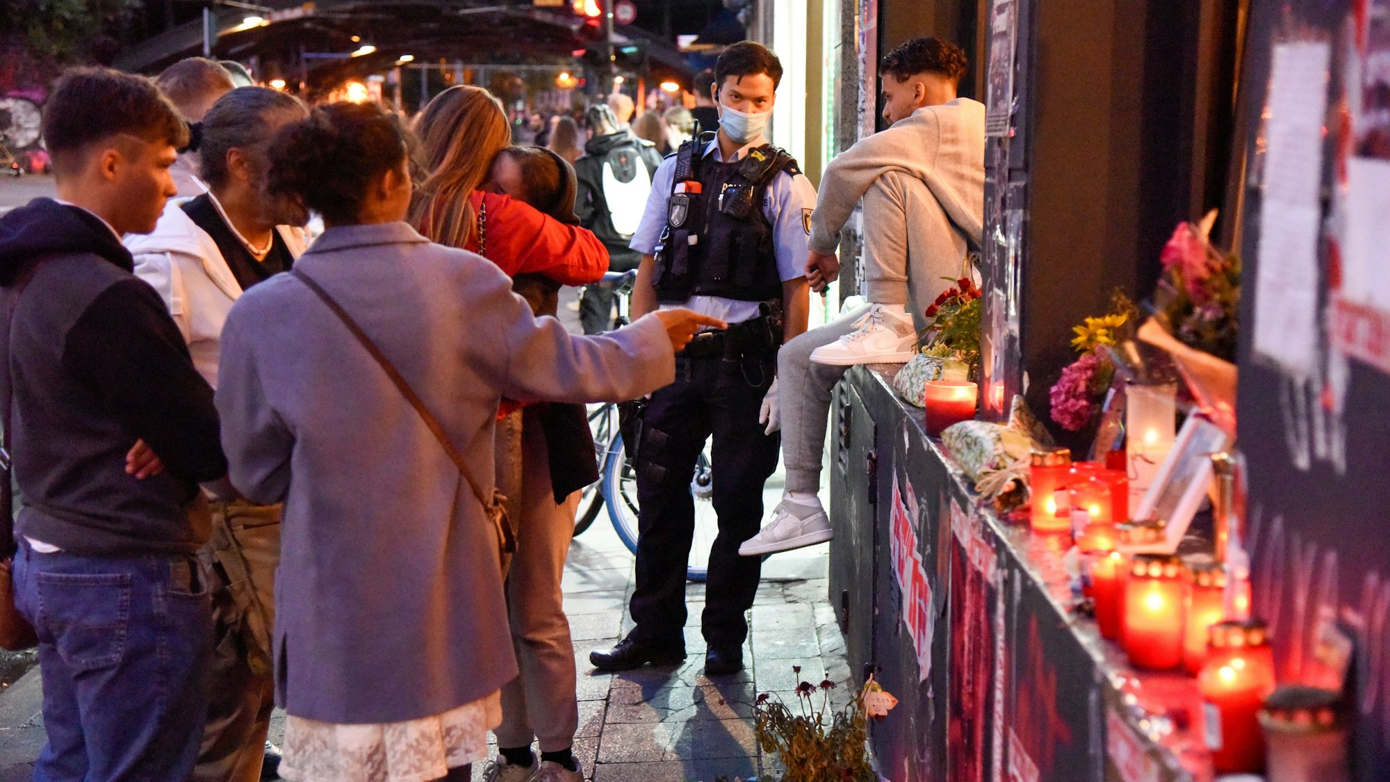 Junge Leute halten am Tatort in der Zülpicher Straße inne.