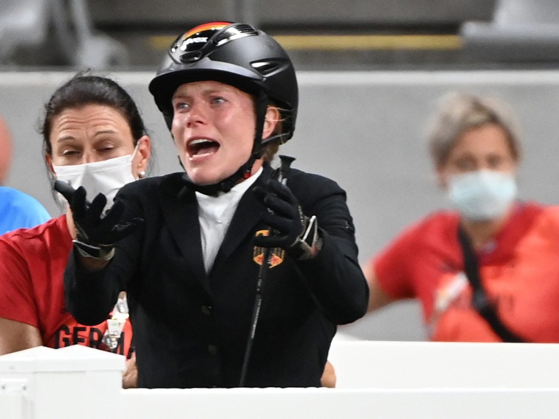 Annika Schleu hebt beim Springreit-Wettbewerb des Olympischen Fünfkampfes in Tokio klagend die Arme.