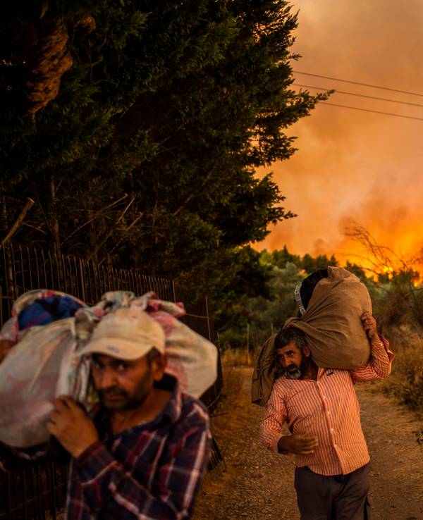 Menschen versuchen Teile ihrer Habe in Sicherheit zu bringen, während ein Waldbrand in einem Waldgebiet nördlich von Athen wütet.