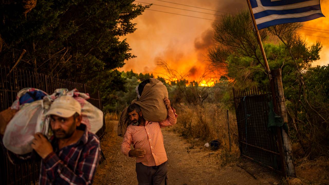 Menschen versuchen Teile ihrer Habe in Sicherheit zu bringen, während ein Waldbrand in einem Waldgebiet nördlich von Athen wütet.