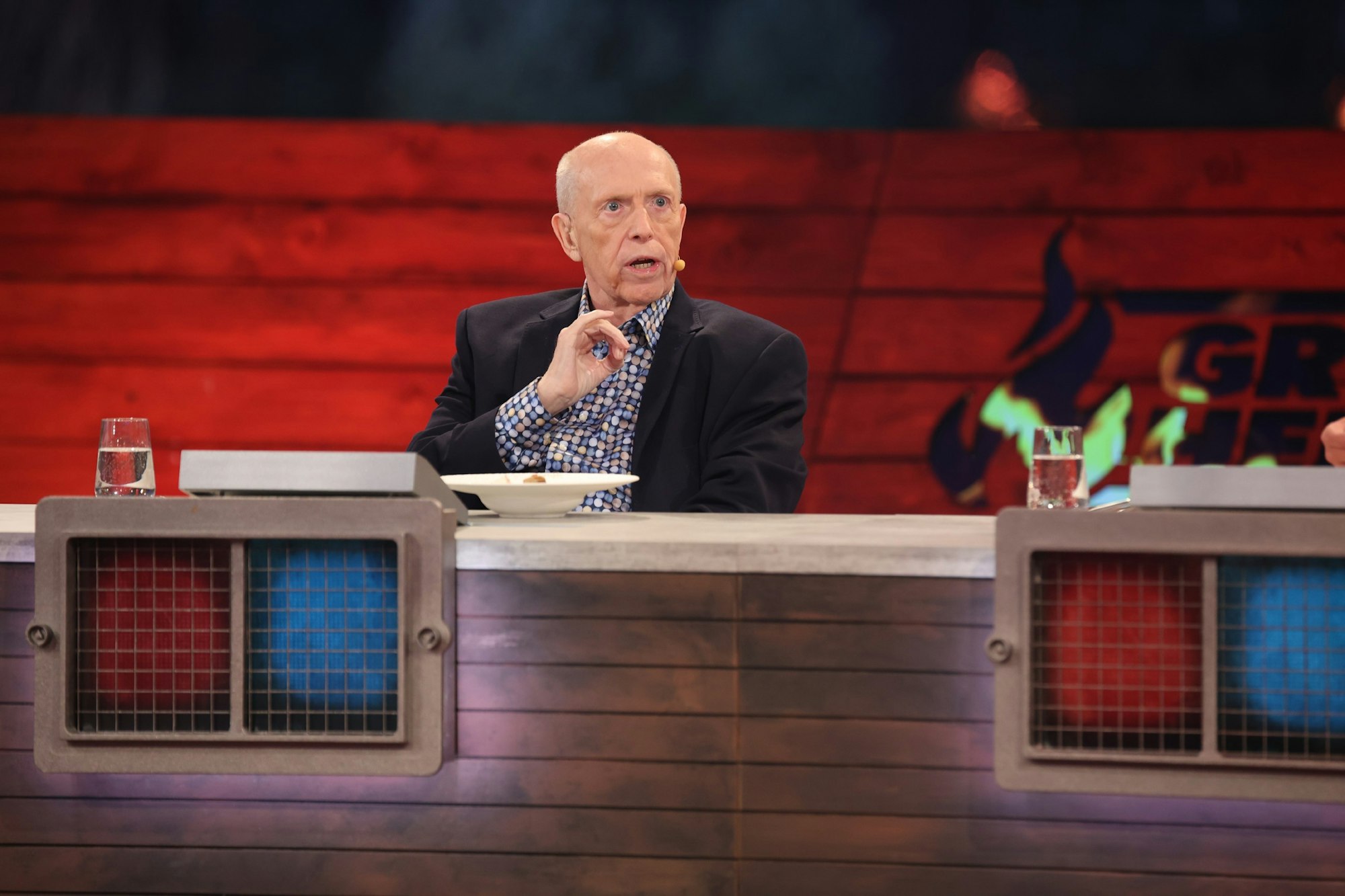 Reiner Calmund hebt die Hand um als Juror bei „Grill den Henssler – Das Sommer-Special” ein Gericht zu bewerten.
