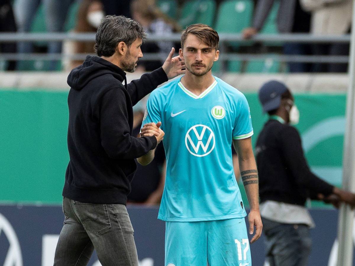 Wolfsburgs Trainer Mark van Bommel (l) steht vor der Einwechslung mit Maximilian Philipp zusammen.