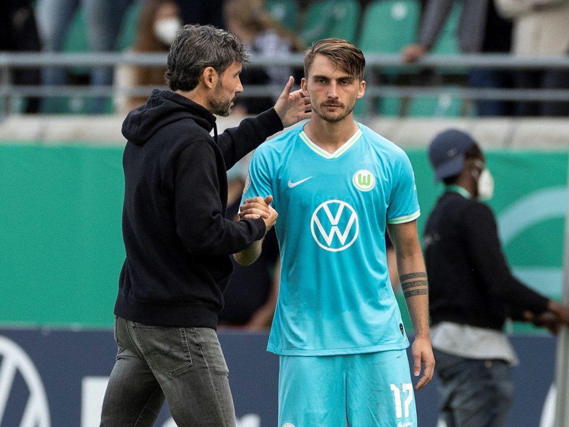Wolfsburgs Trainer Mark van Bommel (l) steht vor der Einwechslung mit Maximilian Philipp zusammen.
