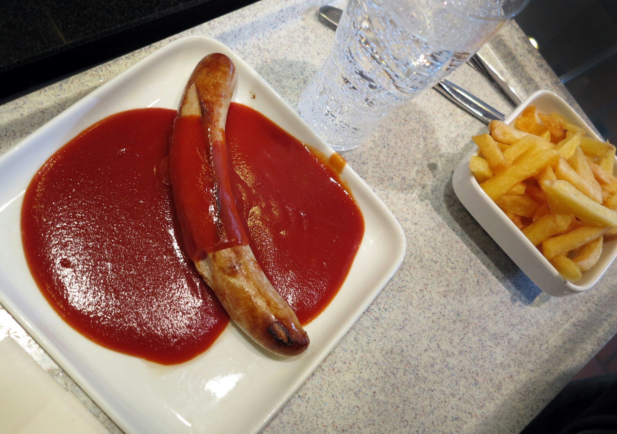 Ein Tablett mit einer Currywurst mit Pommes Frites steht in einer Kantine in Düsseldorf.