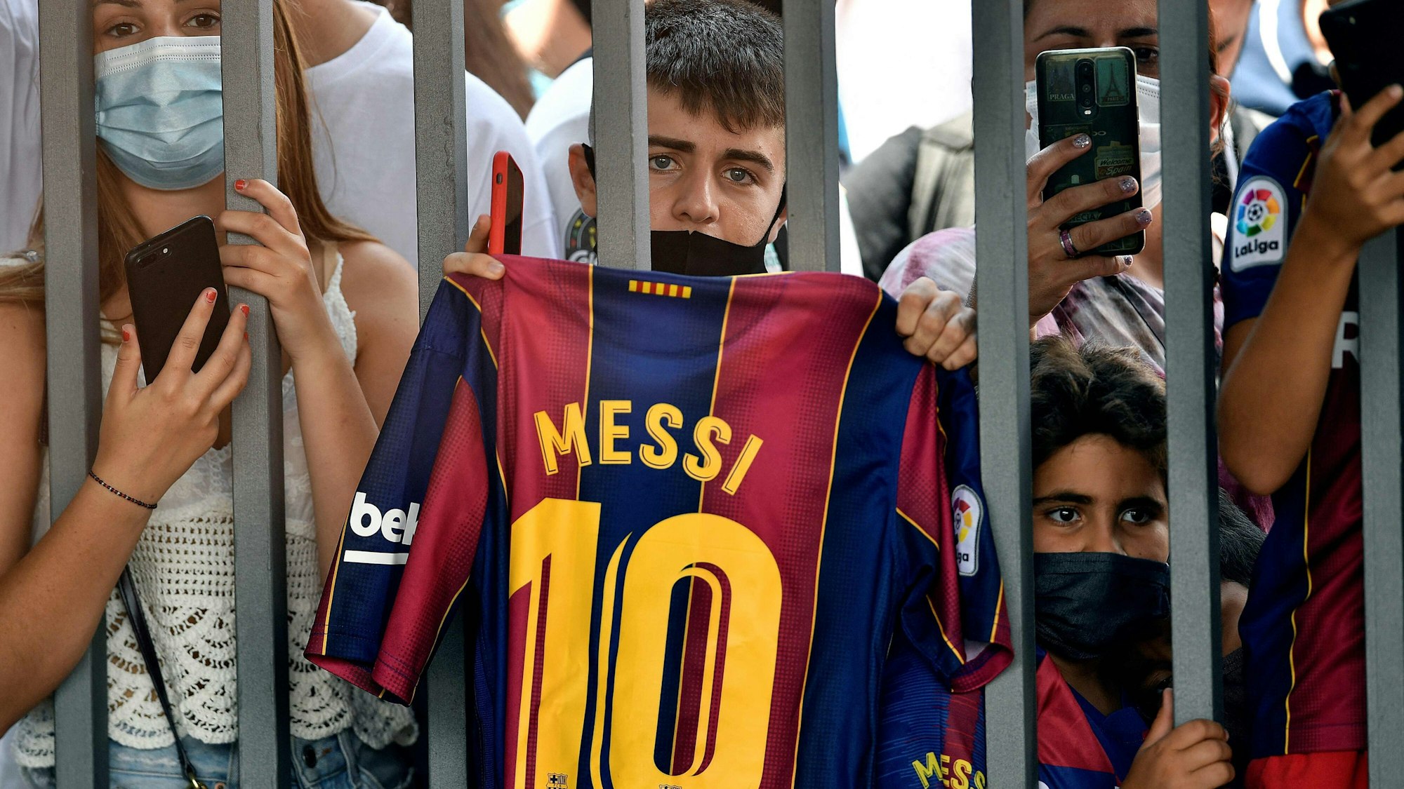 Ein Fan hält ein Barca-Trikot von Lionel Messi in die Luft