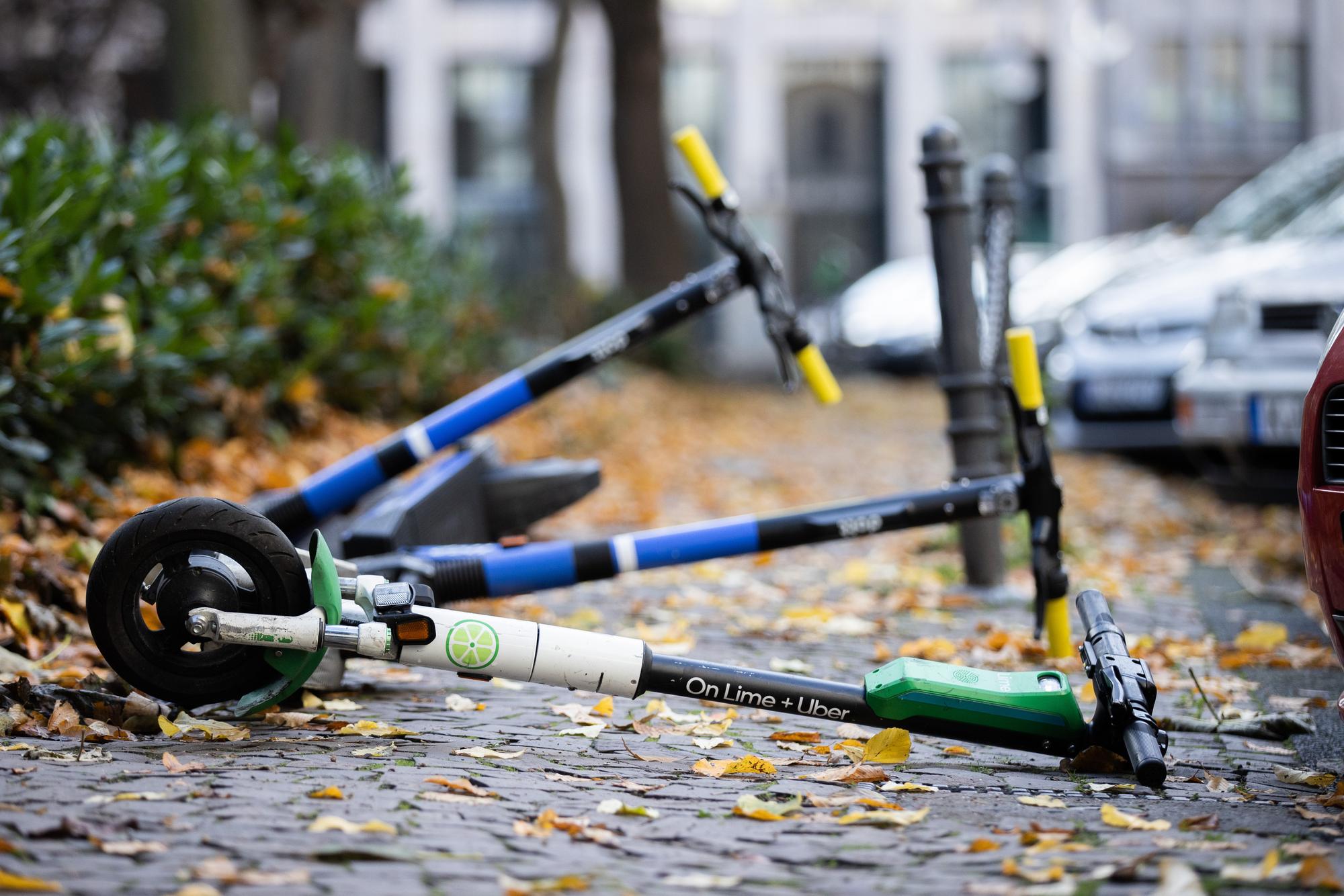 E-Scooter liegen auf einem Gehweg und versperren den Weg.