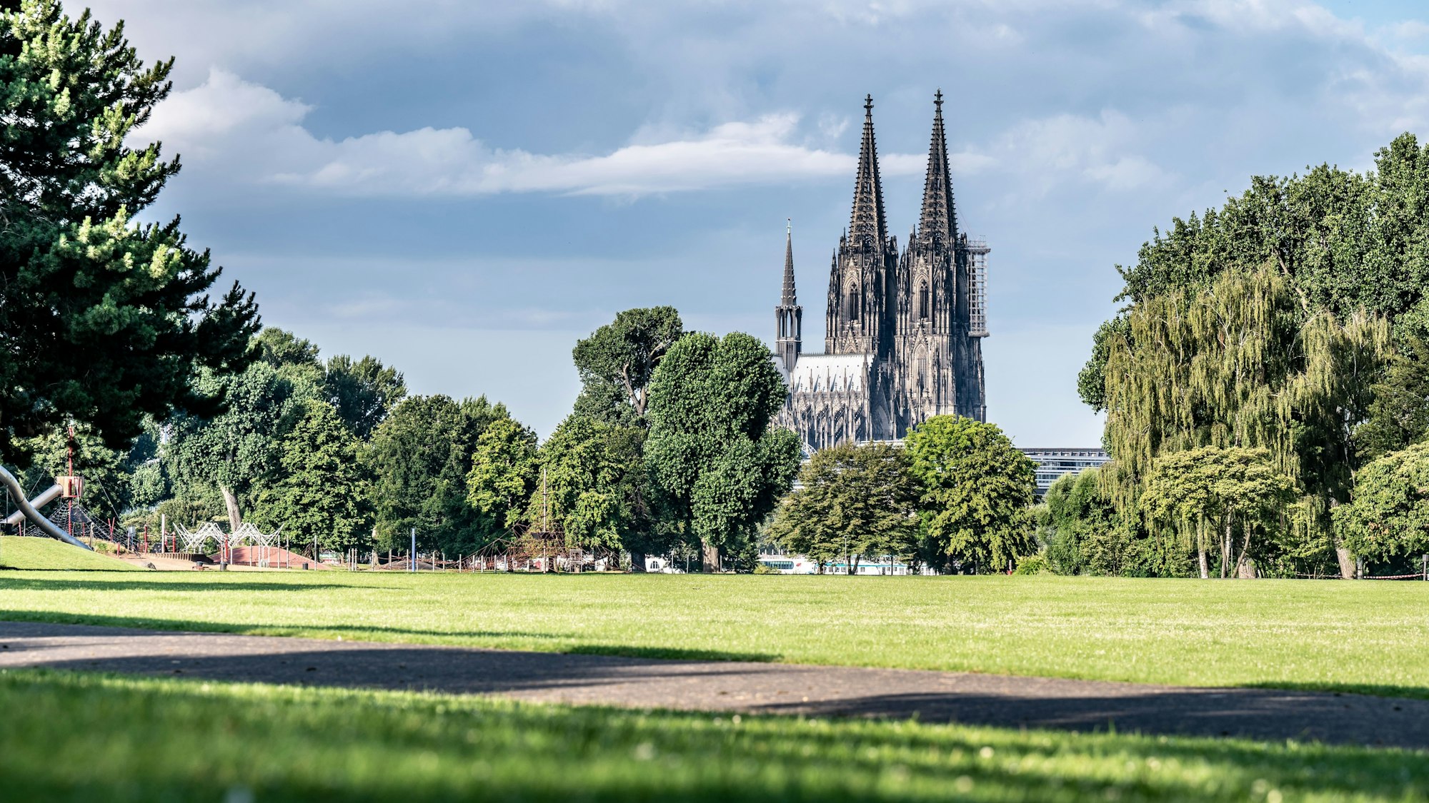 Wolkenbank und Sonnenschein im Kölner Rheinpark mit Blick auf den Dom.