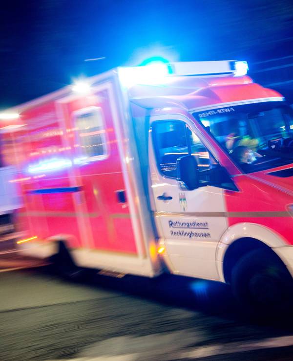 Ein Rettungswagen der Feuerwehr fährt mit Blaulicht durch eine Straße.