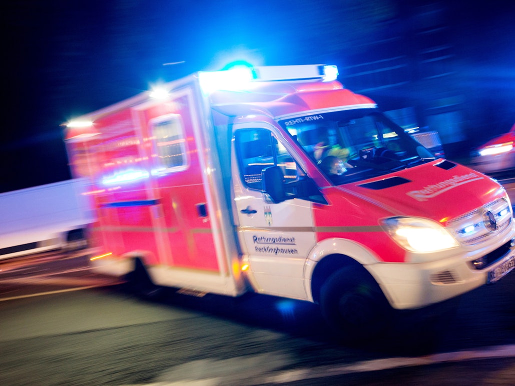 Ein Rettungswagen der Feuerwehr fährt mit Blaulicht durch eine Straße.