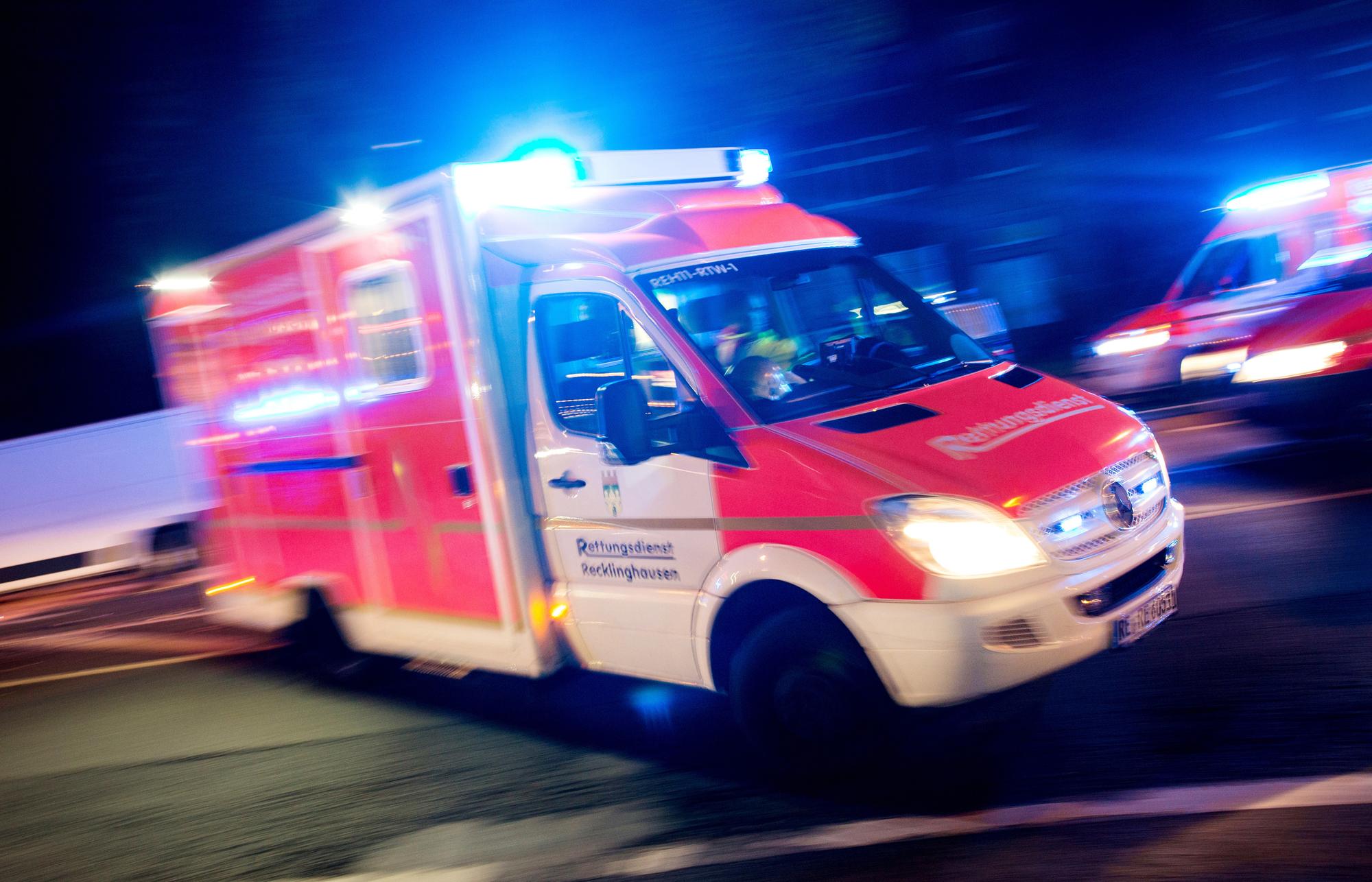 Ein Rettungswagen der Feuerwehr fährt mit Blaulicht durch eine Straße.