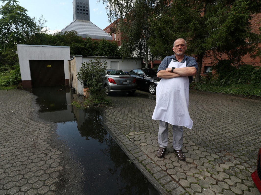 Konditormeister Udo Robl steht neben einer Pfütze und in seinem Geschäft Feine Torte in Niehl.