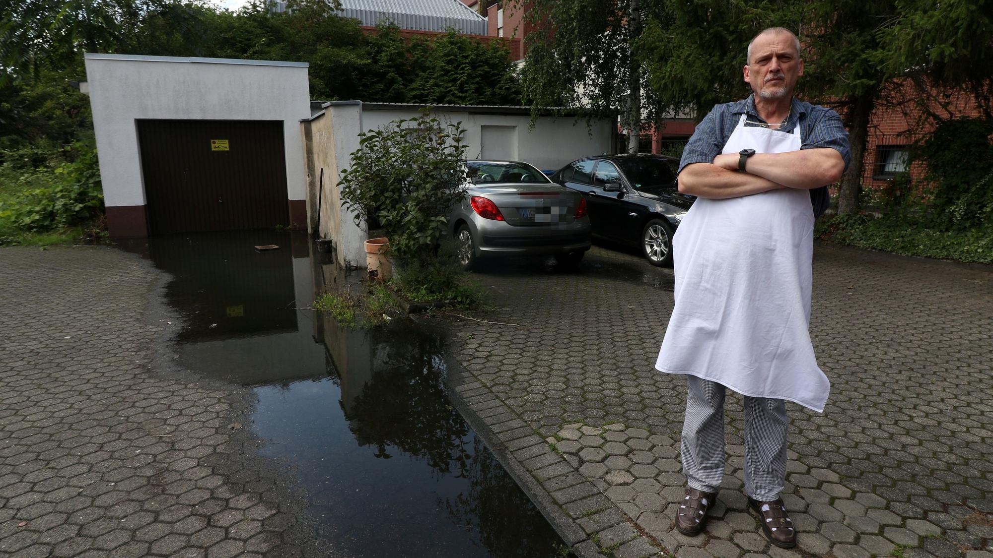 Konditormeister Udo Robl steht neben einer Pfütze und in seinem Geschäft Feine Torte in Niehl.