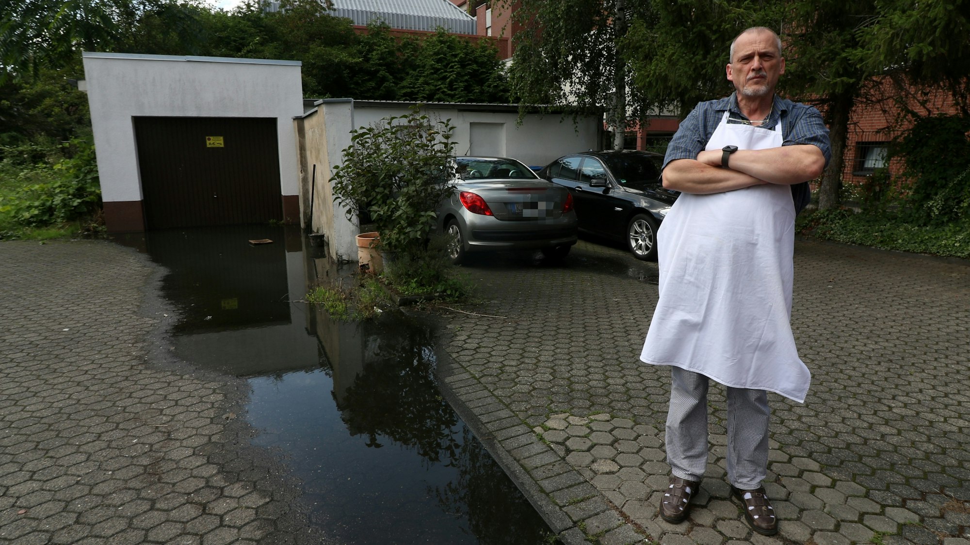 Konditormeister Udo Robl steht neben einer Pfütze und in seinem Geschäft Feine Torte in Niehl.